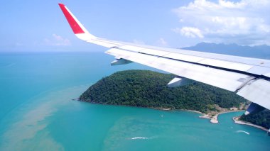 LANGKAWI, MALAYSIA - APR 4th 2015: View from airplane window with wing of an airplane landing on an tropical island