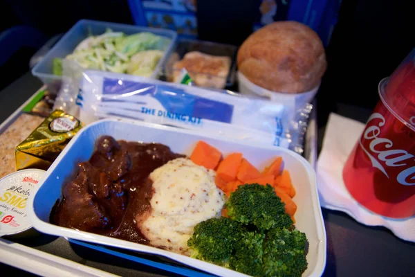 SAN FRANCISCO, CALIFORNIA, UNITED STATES - NOV 24th, 2018: Hot food served on board of economy class airplane on table with salad and cola Royalty Free Stock Images