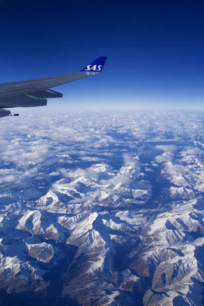CANADA - NOV 24th, 2018: A view of a vast landscape of mountains covered in snow taken from the window of an airplane showing the wing — Stock Photo, Image