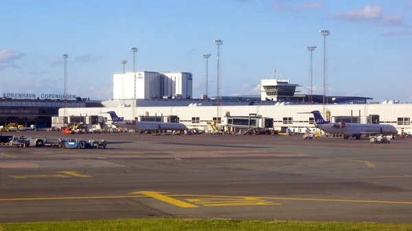 COPENHAGEN, DENMARK - JUL 06th, 2015: Loading aircraft parked by Copenhagen airport building, stairs and luggage carriers nearby — 图库照片