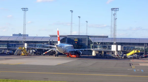 COPENHAGEN, DENMARK - JUL 06th, 2015: Loading aircraft parked by Copenhagen airport building, stairs and luggage carriers nearby — 图库照片