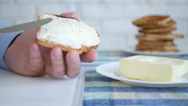 Чоловік розтягує біле масло на смаженому шматочку хліба і їжі — стокове відео
