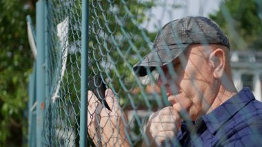 Güvenlik Alanındaki Duvarın Arkasında Cep Telefonu Kullanan Adam Metni