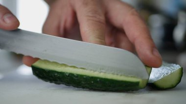 Taze salata için salatalık dilimleri kesen bir bıçak resmi