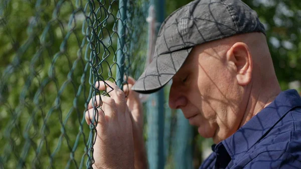 Disappointed Person in a Protection Area Back of a Metallic Fence