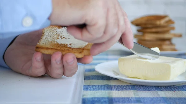 Homens colocam manteiga em uma fatia assada de pão no café da manhã — Fotografia de Stock