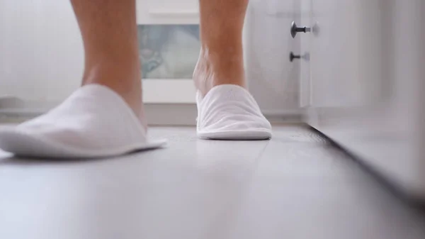 Человек в спальне с белыми тапочками в ногах — стоковое фото