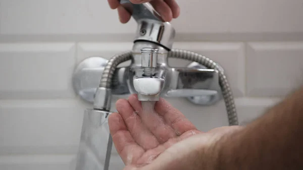 El hombre abre el grifo del baño y se limpia las manos con agua — Foto de Stock