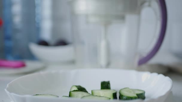 Man i köket förbereder gurka skivor för en färsk sallad — Stockvideo