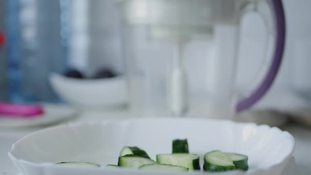 Homem na cozinha preparando fatias de pepino para uma salada fresca — Vídeo de Stock