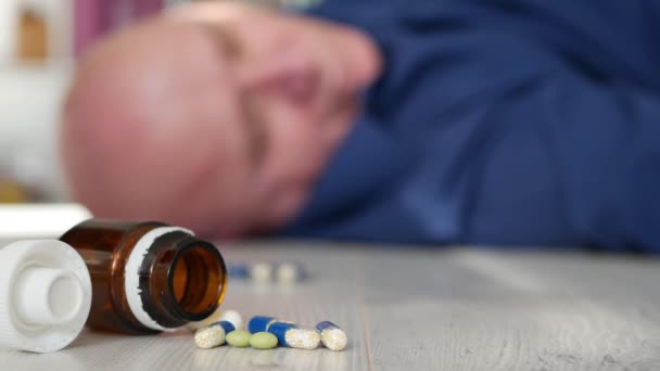 Человек с таблетками на полу, страдающий от сердечного приступа — стоковое видео