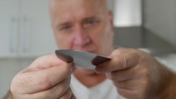 Ο άνθρωπος στην κουζίνα ελέγχει προσεκτικά ένα μεγάλο μαχαίρι — Αρχείο Βίντεο