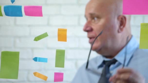 Empresario en sala de reuniones explica y gesticula con gafas — Vídeos de Stock