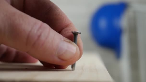 Travailleur Essayez de fixer une planche avec un clou et un marteau 