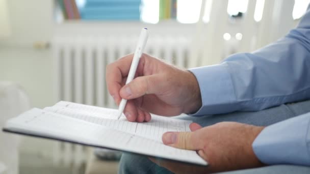 Man in een zakelijke bijeenkomst maakt notities in zijn agenda — Stockvideo