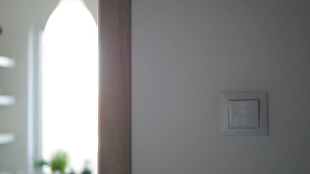 Mann schaltet Licht am Schalter an der Wand aus — Stockvideo