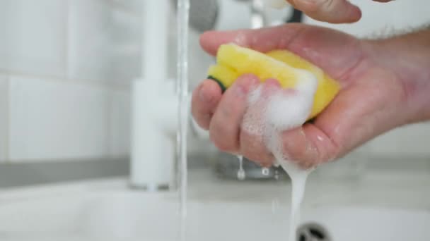 Hombres mano con una esponja lavavajillas empapado con detergente y un montón de espuma — Vídeo de stock
