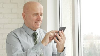 Happy Businessman Smile and Text Using Cellphone Communication in the Office Room