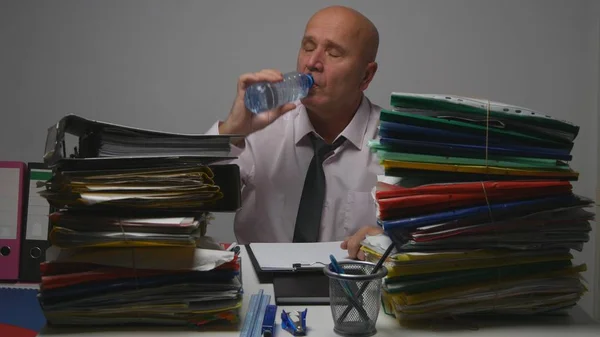 Uomo d'affari assetato sul posto di lavoro che beve acqua fredda fresca da una bottiglia di plastica — Foto Stock