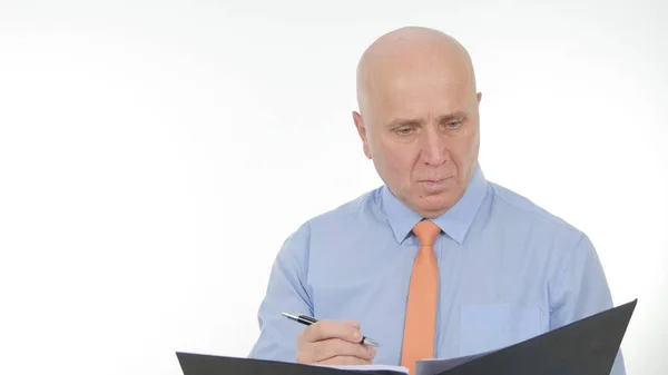 Selbstbewusster Geschäftsmann mit einer Akte in der Hand, die Notizen in Geschäftsdokumente schreibt — Stockfoto