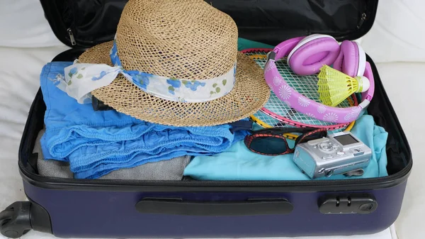 Suitcase Prepared for Going on Holiday with Clothes, Badminton Racket, Sunglasses, and Photo Camera