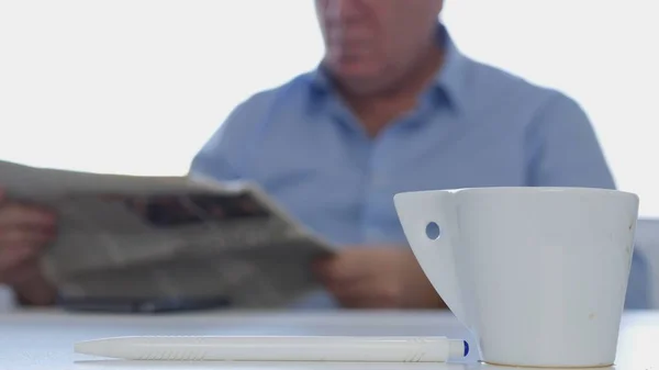 Empresário sentado na mesa com uma xícara de café quente e lendo um jornal financeiro — Fotografia de Stock