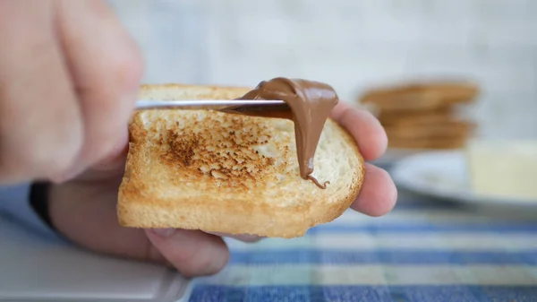 Persona hambrienta comiendo una sabrosa rebanada tostada de pan con deliciosa crema de chocolate — Foto de Stock