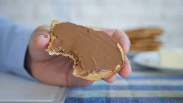 Pessoa com fome comendo uma saborosa fatia de pão torrado com delicioso creme de chocolate — Fotografia de Stock