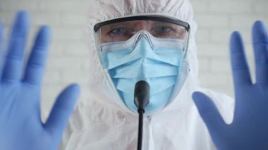 Korunma giysisi giyen ve Coronavirüs salgını hakkında bir tıbbi basın toplantısında konuşan Tıbbi Uzmanla Yavaş Hareket