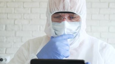 Ağır çekim doktoru koruyucu giysi, eldiven, maske ve gözlük takıyor. Hastane karantinasında cep telefonu kullanıyor.