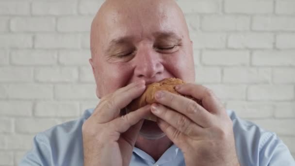 Vyhladovělý člověk jíst chutný hamburger, propojení jeho prsty Užijte si lahodnou svačinu v restauraci rychlého občerstvení — Stock video