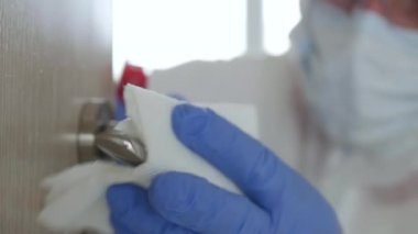 Koruyucu giysi, eldiven, maske ve gözlük takan adam hastane karantinasında antibakteriyel çözümle dezenfekte edici kapı kolu,