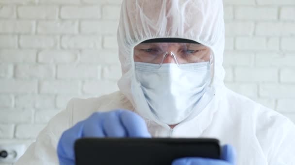 Doctor dragen Protection Suit, Handschoenen, Masker, en bril in het ziekenhuis quarantaine Met behulp van een mobiele telefoon — Stockvideo