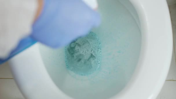 Muž v ochranných rukavicích dezinfikuje záchodovou mísu antibiotickým roztokem — Stock video