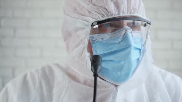Медленное движение с врачом в защитном костюме и разговоры на медицинской пресс-конференции об эпидемии коронавируса — стоковое видео