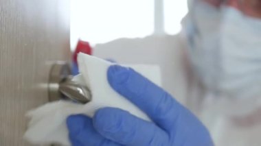 Koruyucu giysi, eldiven, maske ve gözlük takan adam hastane karantinasında antibakteriyel çözümle dezenfekte edici kapı kolu