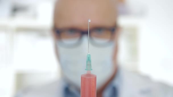 Medico che indossa guanti e maschera facciale Tenere in mano un'iniezione con un vaccino, un antidoto e un trattamento per la pandemia virale — Video Stock