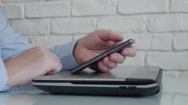 İş Adamı Evden Cep Telefonu Mesajlaşması Kullanıyor ve Çevrimiçi Çalışıyor, Telefonla ve Laptop 'tan Ofisle Çevrimiçi Bağlantıya Erişiyor