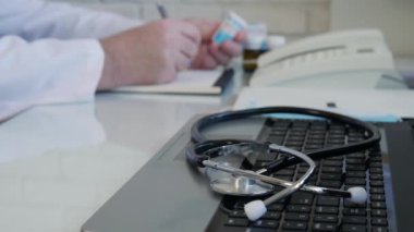 Slow Motion Doctor bazı ilaçlara bakıyor ve bir tedavi öneriyor, doktor hastane danışma odasında tıbbi bir tarif yazıyor.