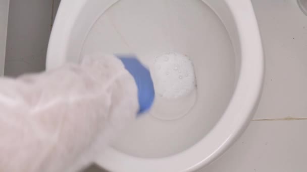 保護服を着た人とのスローモーション浴室内のトイレボウルを消毒し、消毒剤でトイレボウルの内部をきれいにする — ストック動画