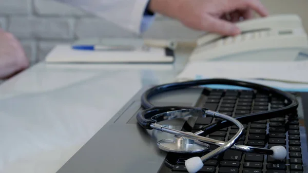 Image floue avec un médecin au bureau médical utilisant le téléphone de bureau et composant un numéro de téléphone — Photo