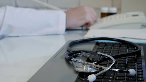 Image floue avec un médecin au bureau médical utilisant le téléphone de bureau et composant un numéro de téléphone — Photo