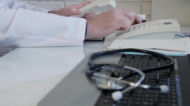 Медленное движение с врачом в больнице Набирая номер телефона с помощью стационарного телефона, врач делает телефонный звонок в медицинском кабинете — стоковое видео