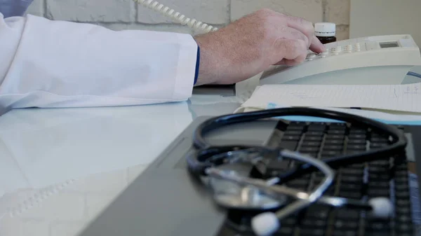 Médecin au bureau médical utilisant le téléphone de bureau et composant un numéro de téléphone — Photo