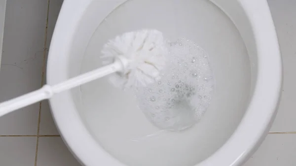 Человек с защитной одеждой и перчатками в руках дезинфекция унитаза в ванной комнате с помощью щетки туалета — стоковое фото