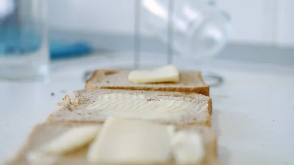 Café da manhã com manteiga no brinde, espalhando margarina em uma fatia fresca de pão na cozinha — Fotografia de Stock