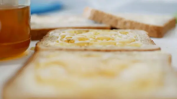 Café da manhã com homem espalhando mel doce no brinde, mel fresco em uma fatia de pão na cozinha — Fotografia de Stock