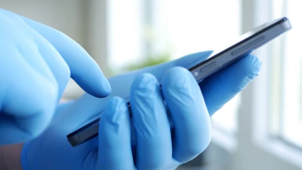 Social Distancing Lifestyle, Man Hands Protected with Gloves Texting on a Cellphone, Person Using Mobile in a Hospital Room