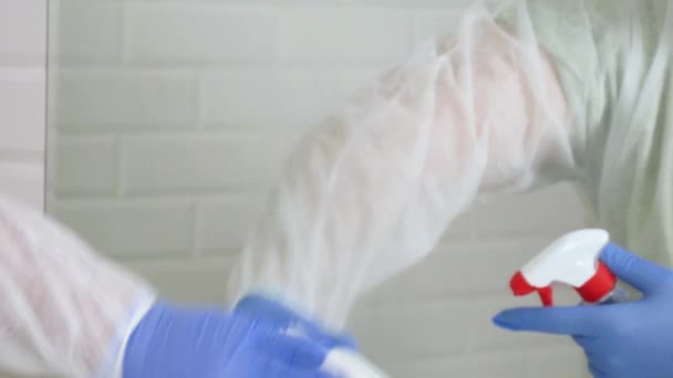 Slow Motion med en person bär skyddskläder desinficera en spegel i ett badrum, Städning av insidan av en toalett rum i en karantän sjukhus — Stockvideo