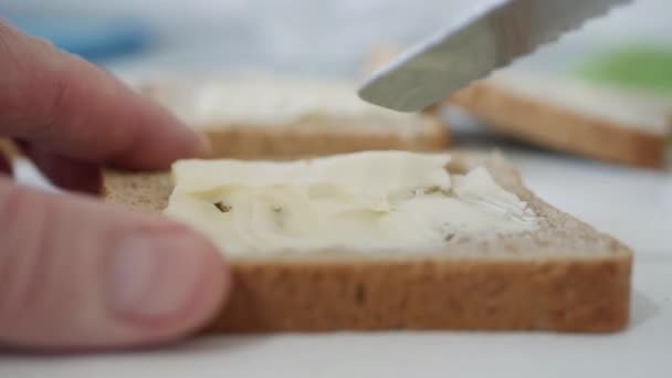 Desayuno por la mañana con mantequilla en el brindis, esparciendo Margarina en una rebanada fresca de pan en la cocina — Vídeo de stock